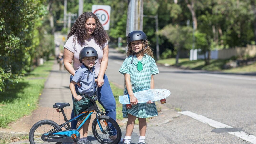 Mum and two children outside holding a bike and skateboard