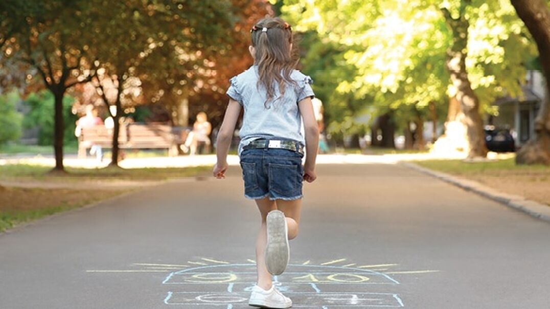 Young girl playing hopscotch outside