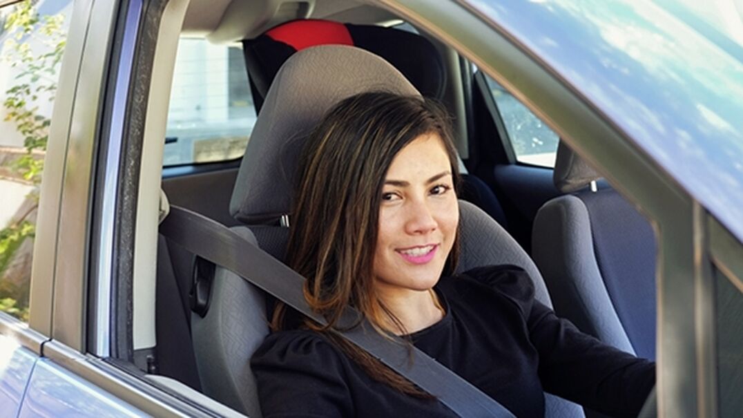 Teenage girl smiling in drivers seat of car