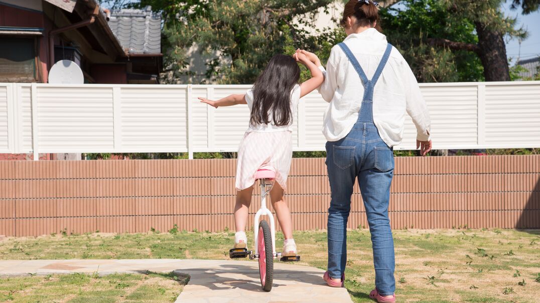 Woman holding child's hand riding a bike