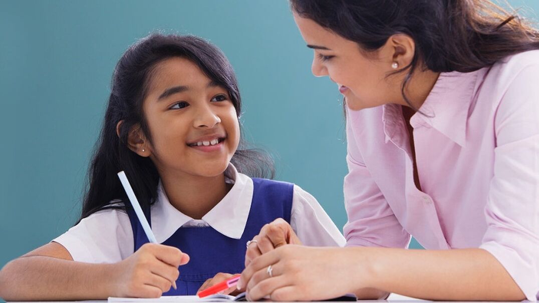 Young girl student smiling at female teacher