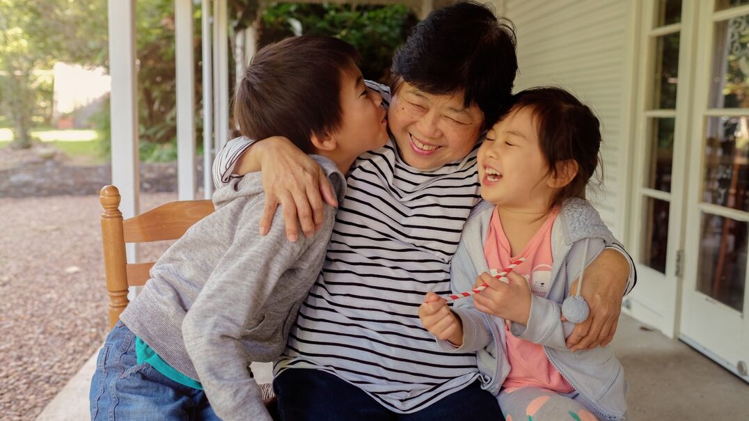 Grandmother with two young children smiling and laughing