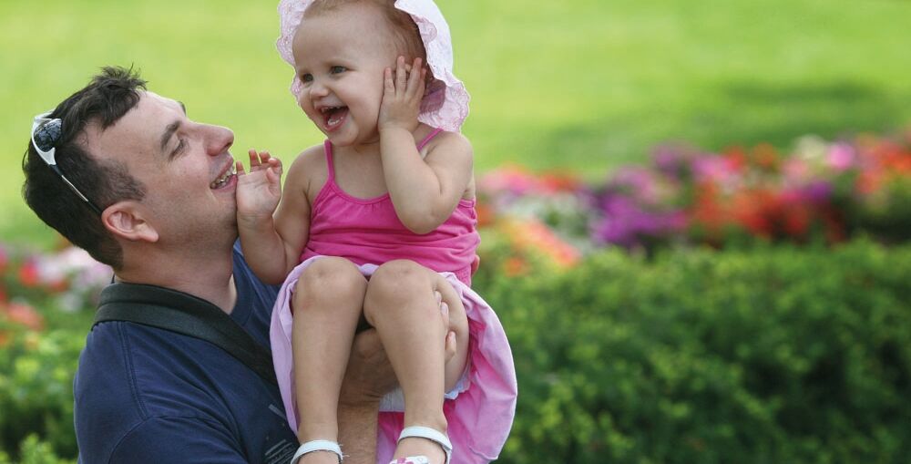 Father holding baby girl at a park bench