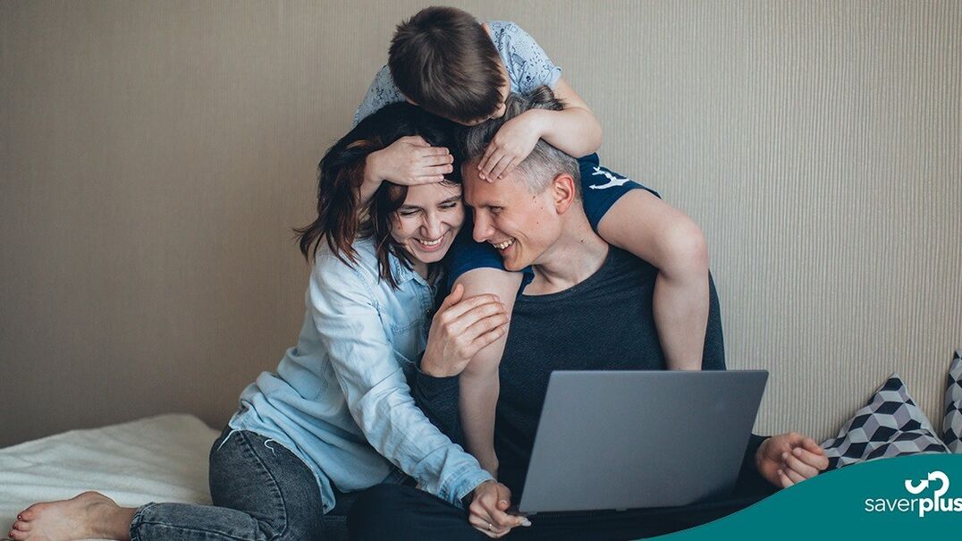 Mother and father playing with son whilst on laptop