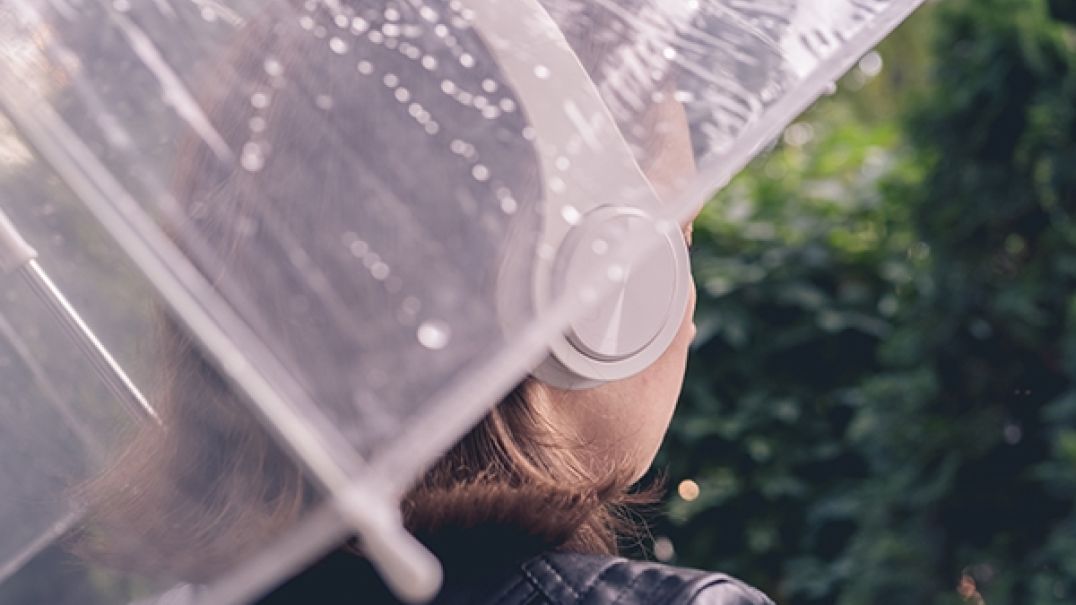 Person wearing headphone and holding an umbrella